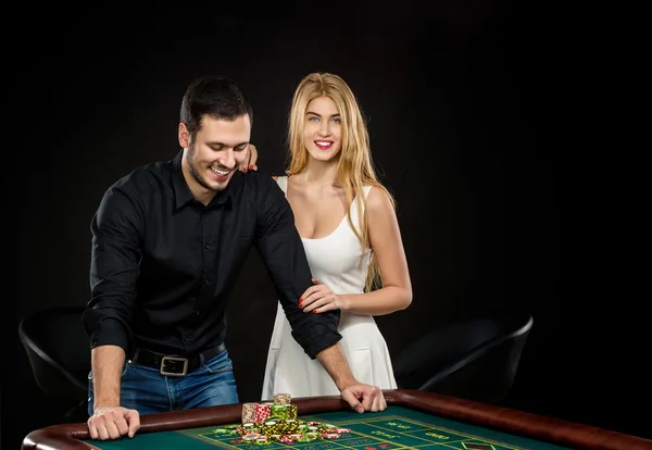 Pareja joven celebrando victoria en la mesa de ruleta en el casino . — Foto de Stock