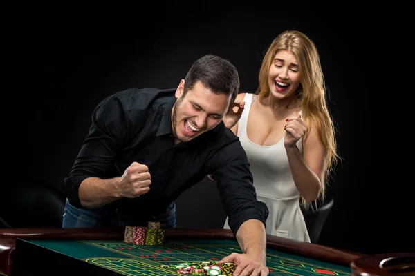 Pareja joven celebrando victoria en la mesa de ruleta en el casino . — Foto de Stock