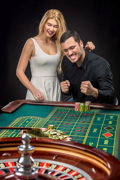 Pareja joven celebrando victoria en la mesa de ruleta en el casino . — Foto de Stock