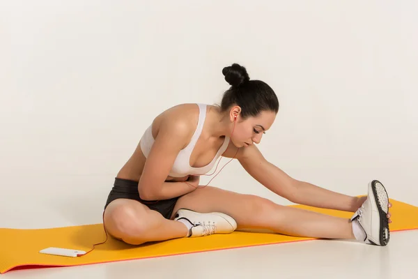 Mujer atractiva haciendo ejercicios. Morena cuerpo en forma en estera de yoga — Foto de Stock