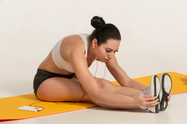Aantrekkelijke vrouw doen oefeningen. Brunette fit lichaam op yoga mat — Stockfoto