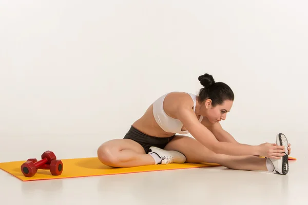 Mujer atractiva haciendo ejercicios. Morena cuerpo en forma en estera de yoga — Foto de Stock