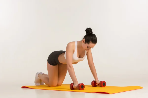 Silná mladá žena dělá push up cvičení s činkami. — Stock fotografie