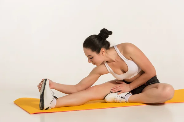 Aantrekkelijke vrouw doen oefeningen. Brunette fit lichaam op yoga mat — Stockfoto