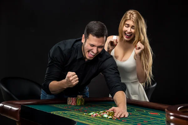 Pareja joven celebrando victoria en la mesa de ruleta en el casino . — Foto de Stock