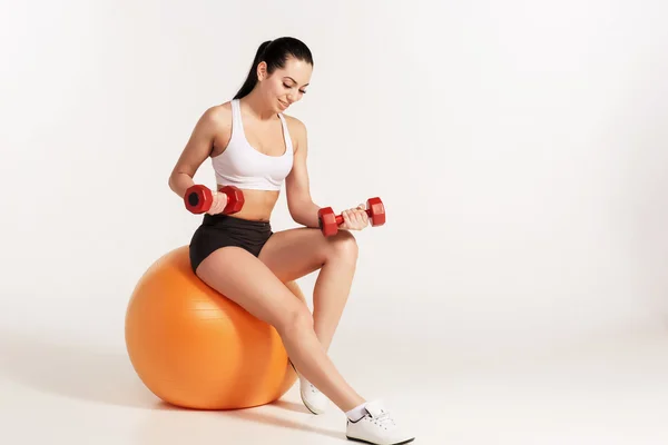 Jonge mooie Sportvrouw met halters uitoefenen op fitball — Stockfoto