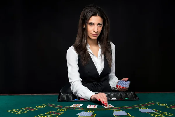 La hermosa chica, distribuidor, detrás de una mesa de póquer — Foto de Stock