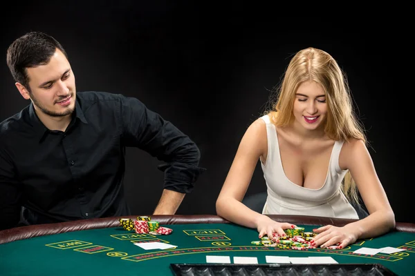 Pareja joven jugando póquer, mujer tomando fichas de póquer después de ganar — Foto de Stock