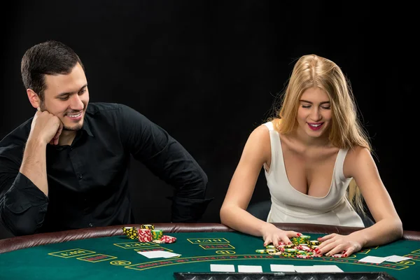 Pareja joven jugando póquer, mujer tomando fichas de póquer después de ganar — Foto de Stock
