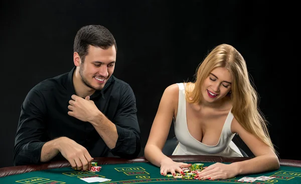 Pareja joven jugando póquer, mujer tomando fichas de póquer después de ganar — Foto de Stock