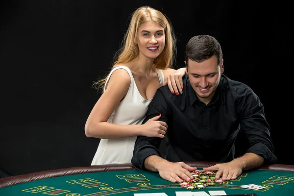 Pareja joven jugando póquer. Hombre tomando fichas de póquer después de ganar — Foto de Stock