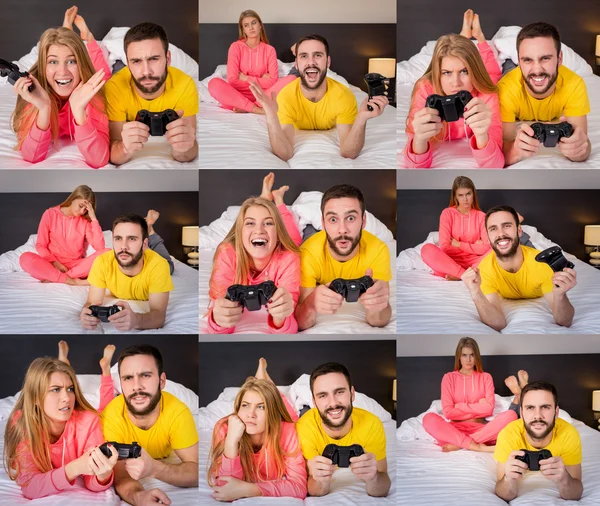 Молодая пара, играющая в видеоигры в постели — стоковое фото