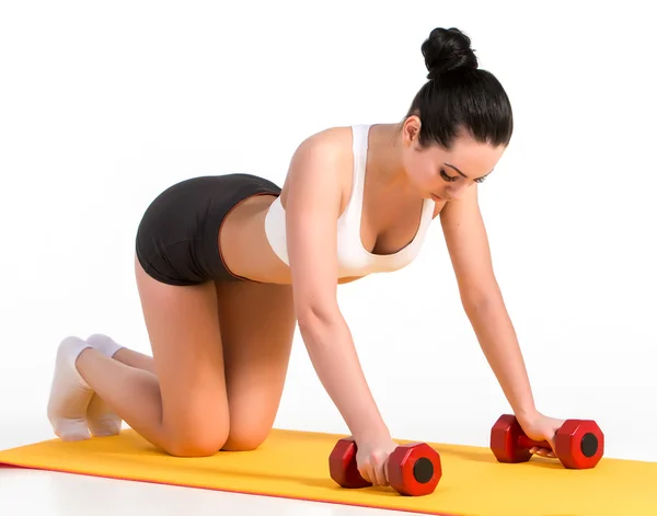 Sterke jonge vrouw doet push ups oefening met halters. — Stockfoto