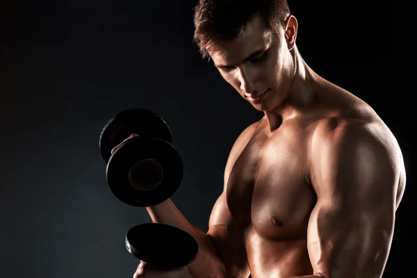 Могучий фитнес-человек показывает свое жадное тело с гантелями — стоковое фото