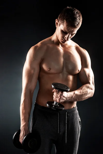 Могучий фитнес-человек показывает свое жадное тело с гантелями — стоковое фото