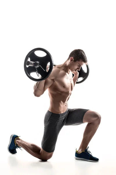 Muscular man standing on knee, holding barbell over his head — Stok fotoğraf