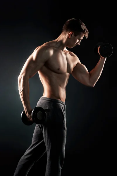 Атлетик показывает мускулистое тело и делает упражнения с тупым Стоковое Изображение