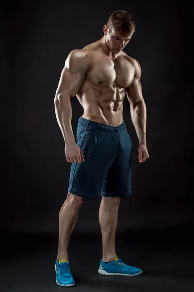 Muscular culturista chico haciendo posando sobre fondo negro — Foto de Stock