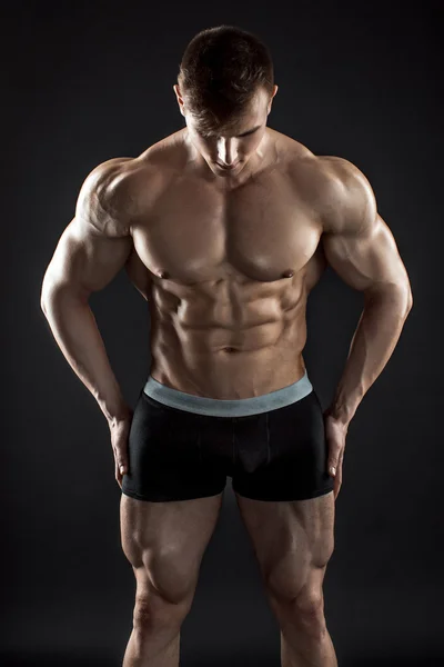 Musclé bodybuilder gars faisant posant sur fond noir — Photo