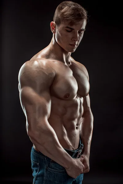 Muscular culturista chico haciendo posando sobre fondo negro — Foto de Stock