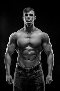 Siyah arka plan üzerinde poz yapan kaslı vücut geliştirmeci adam