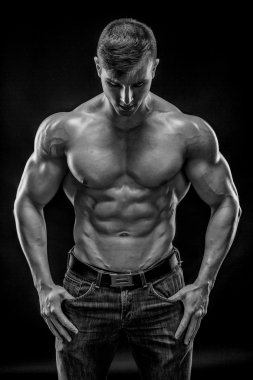 Siyah arka plan üzerinde poz yapan kaslı vücut geliştirmeci adam
