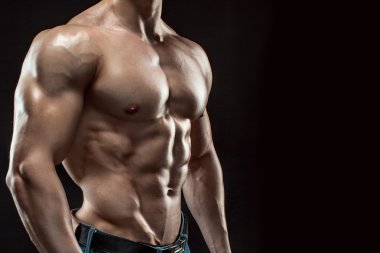 Siyah arka plan üzerinde poz yapan kaslı vücut geliştirmeci adam