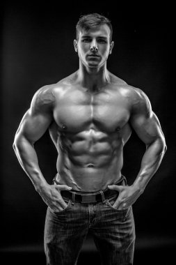 Siyah arka plan üzerinde poz yapan kaslı vücut geliştirmeci adam