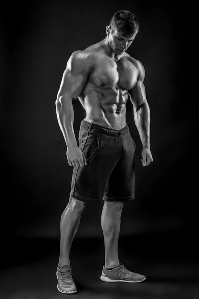 Musclé bodybuilder gars faisant posant sur fond noir — Photo