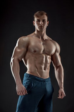 Siyah arka plan üzerinde poz yapan kaslı vücut geliştirmeci adam