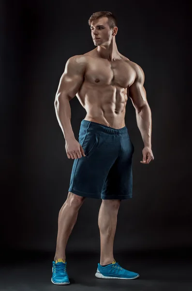 Muscular culturista chico haciendo posando sobre fondo negro — Foto de Stock