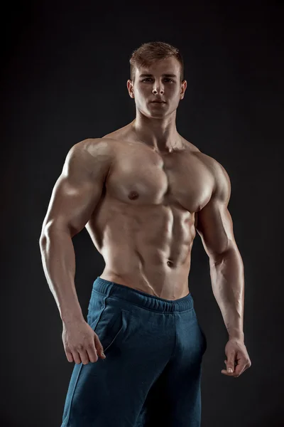 Muscular culturista chico haciendo posando sobre fondo negro — Foto de Stock