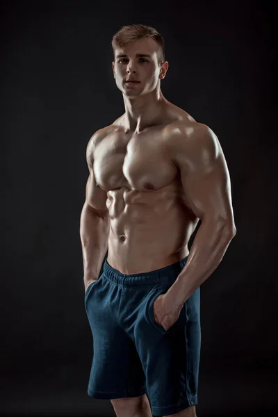 Muscular bodybuilder guy doing posing over black background — Stock Photo, Image