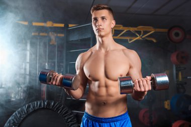 Spor salonunda dumbbells ile ağır egzersiz yapan erkek