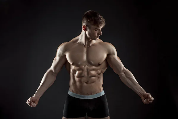 Muscular bodybuilder guy doing posing over black background — Stock Photo, Image