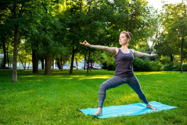 Genç kadının yaz Şehir Parkı yoga egzersizleri yapması.