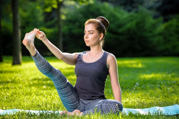 Mujer joven haciendo ejercicios de yoga en el parque de verano de la ciudad . — Foto de Stock