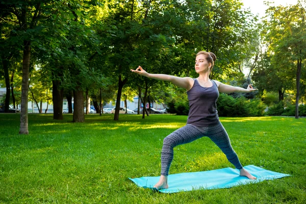 Ung kvinna gör yogaövningar i sommar stadsparken. — Stockfoto