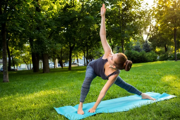 Young woman doing yoga exercises in the summer city park. — Stock Photo, Image