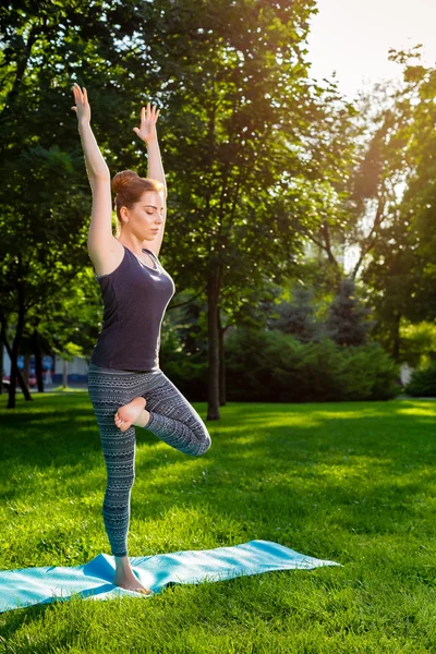 Junge Frau macht Yoga-Übungen im sommerlichen Stadtpark. — Stockfoto