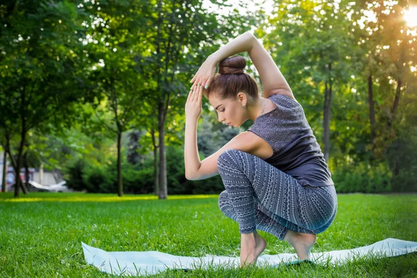 Junge Frau macht Yoga-Übungen im sommerlichen Stadtpark. — Stockfoto