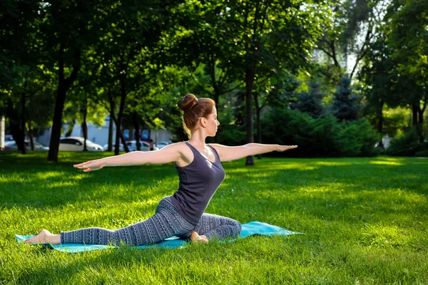 Mujer joven haciendo ejercicios de yoga en el parque de verano de la ciudad . — Foto de Stock