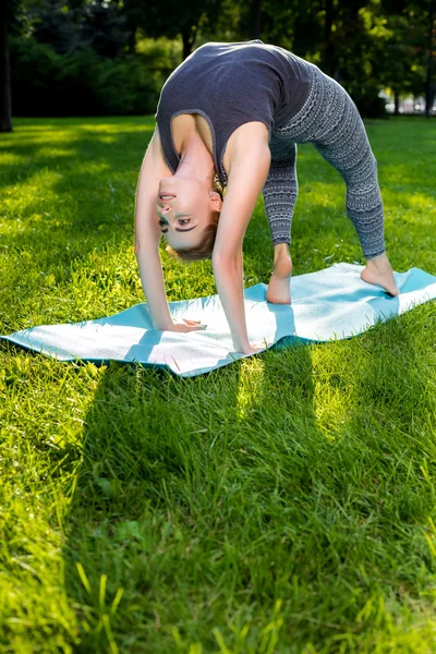 Genç kadının yaz Şehir Parkı yoga egzersizleri yapması.