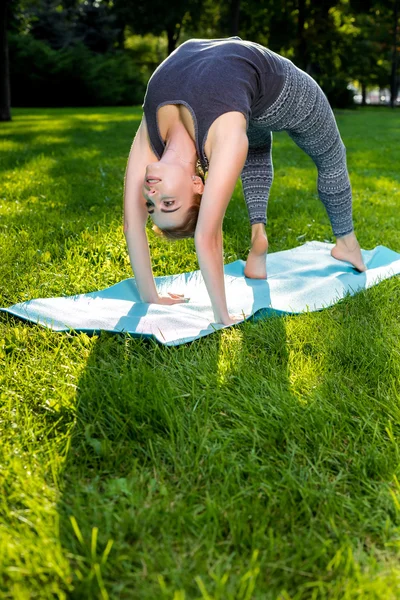 stock image Young woman doing yoga exercises in the summer city park.