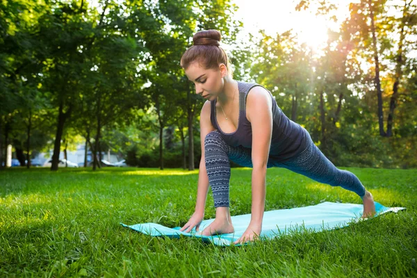 Mujer joven haciendo ejercicios de yoga en el parque de verano de la ciudad . — Foto de Stock