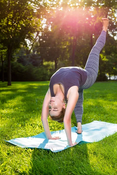 Mujer joven haciendo ejercicios de yoga en el parque de verano de la ciudad . — Foto de Stock