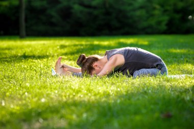 Genç kadının yaz Şehir Parkı yoga egzersizleri yapması.