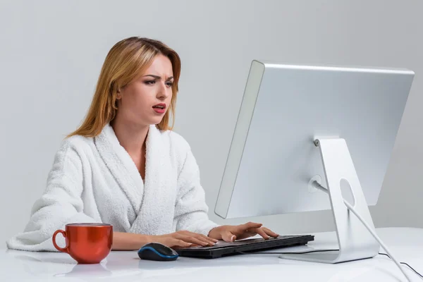 Молода жінка сидить за столом і використовує комп'ютер — стокове фото