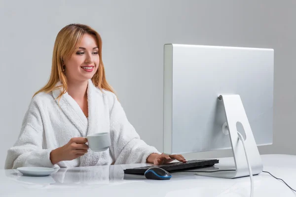 Молода жінка сидить за столом і використовує комп'ютер — стокове фото