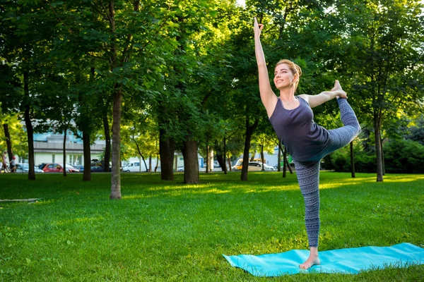 Fiatal nő csinál jóga gyakorlatok-a nyári városi park. — Stock Fotó